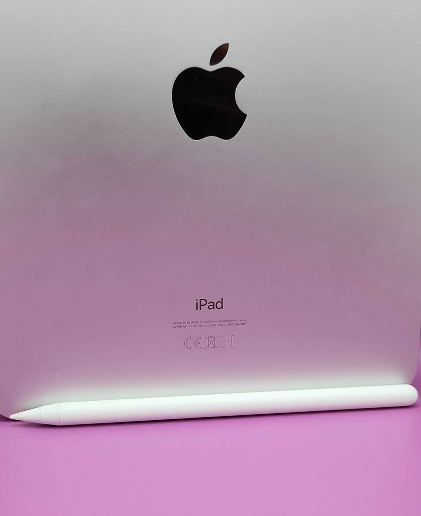 Getestet: Ein iPad Stylus Pen liegt auf einer pinkfarbenen Oberfläche vor einem iPad. Hintergrund.