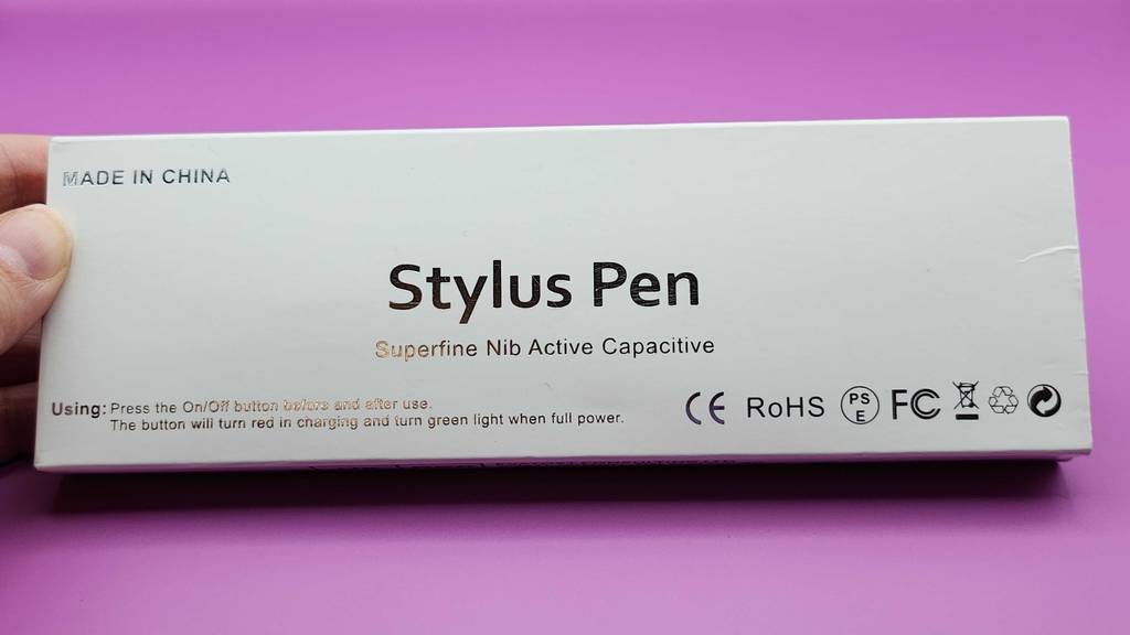 Im Test: eine iPad-Stylus-Pen-Originalverpackung in einer Hand vor einem pinkfarbenen Hintergrund.
