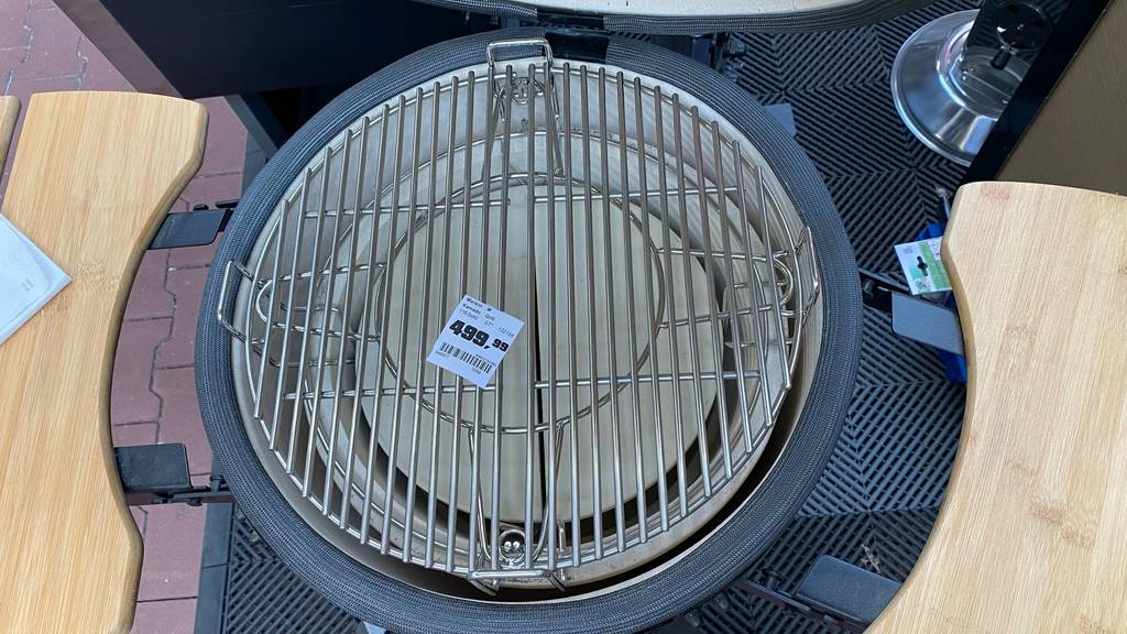 Sicht von oben auf das Edelstahl-Grillrost eines getesteten Keramikgrills mit beidseitigen Ablageflächen aus Holz.