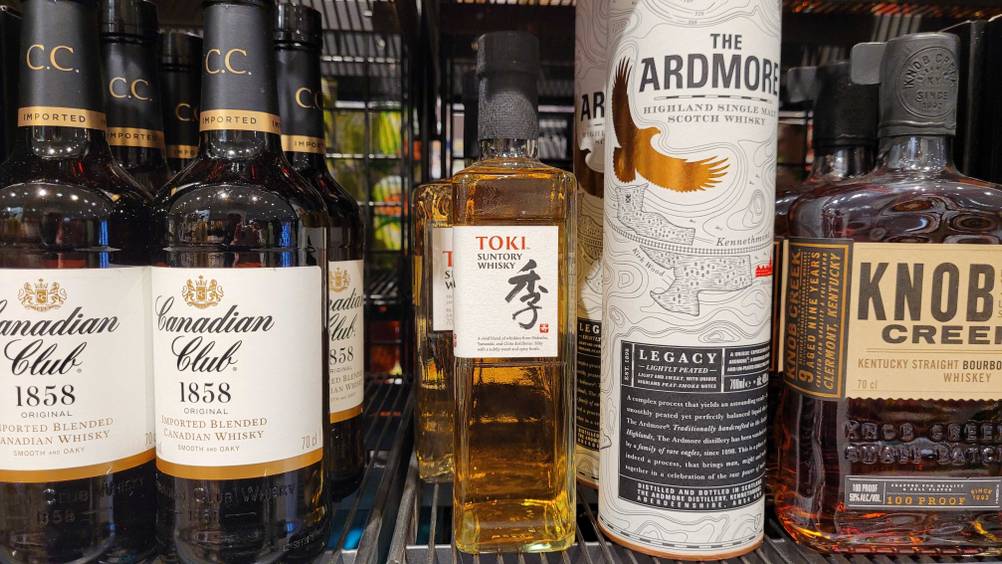 Japanischer Whisky getestet: Seitenansicht einer Flasche in einem Regal neben anderen Produkten.