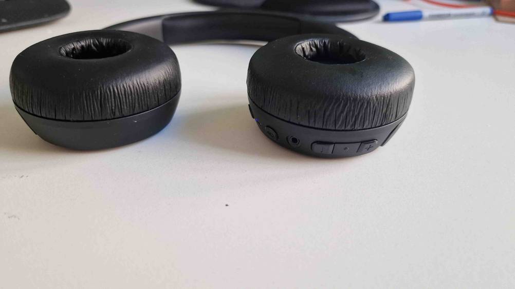 JBL-Bluetooth-Kopfhörer-Test: Ein Kopfhörer flach liegend mit Nahaufnahme der Bedienelemente.