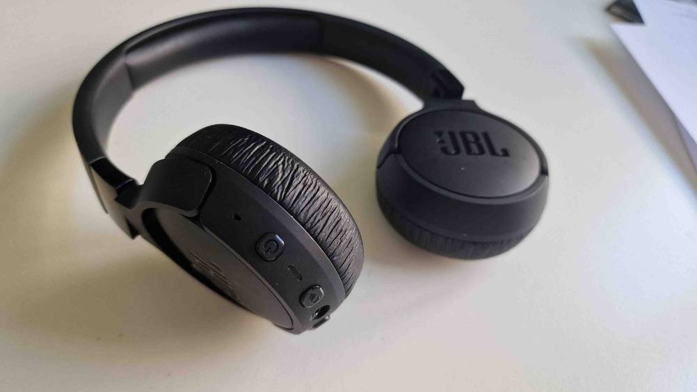 JBL-Bluetooth-Kopfhörer getestet: Nahaufnahme der Bedienelemente eines Kopfhörers auf einer hellen Fläche.