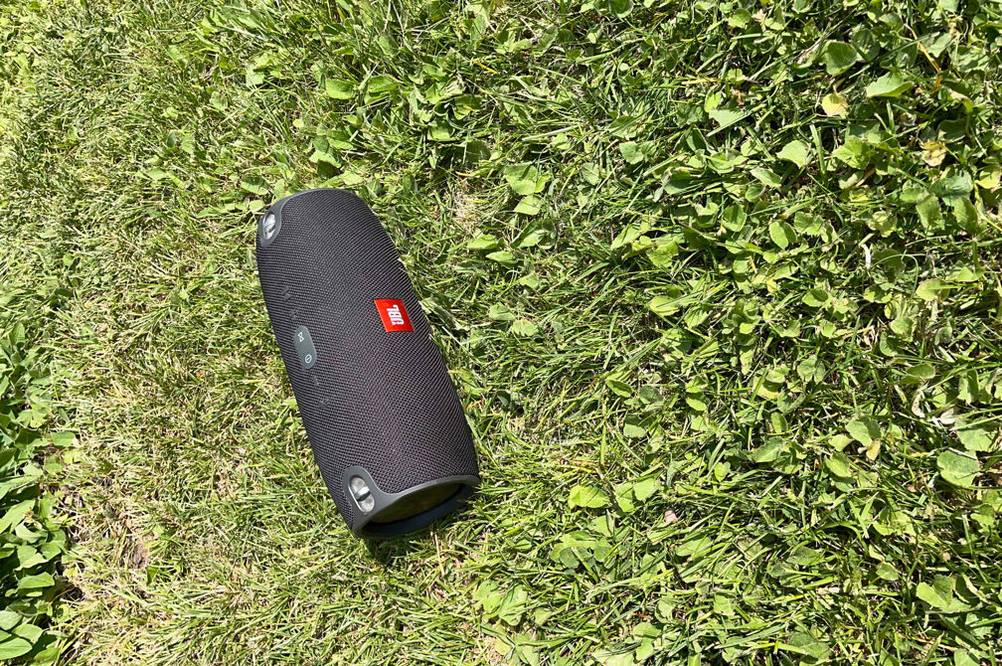 Ein getesteter JBL-Bluetooth-Lautsprecher liegt auf einer Wiese.