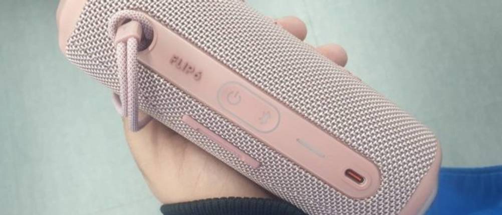 Ein getesteter rosaner Bluetooth-Lautsprecher liegt in einer Hand