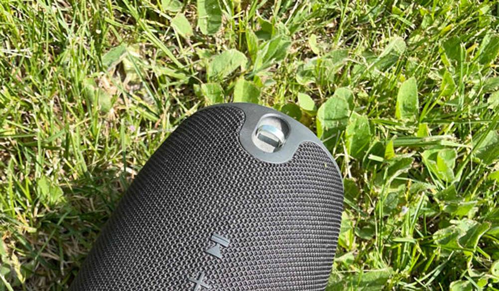 Der JBL-Bluetoothlautsprecher ist im Gras – im Mittelpunkt die Gurtaufhängung.