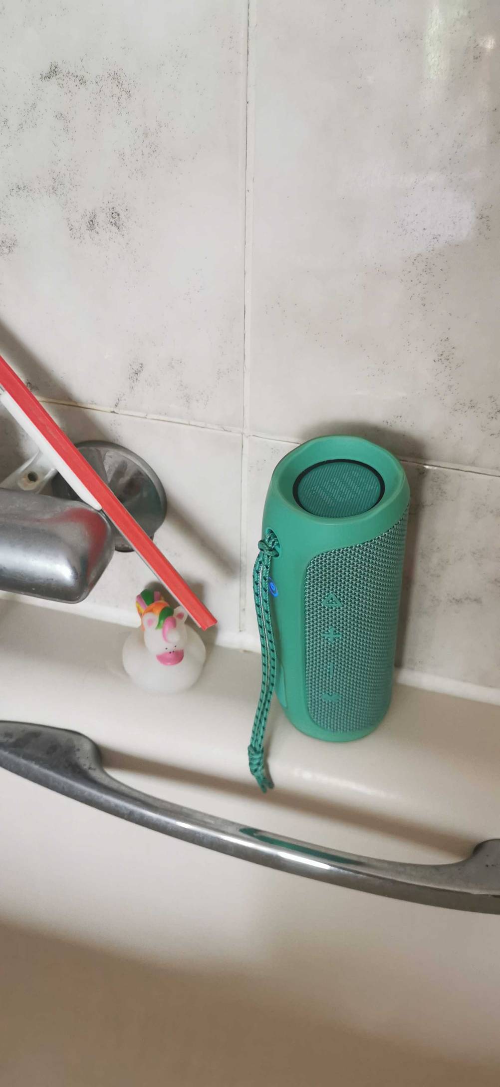 Ein wasserdichter Bluetooth Lautsprecher steht zum testen am Rand einer Badewanne.