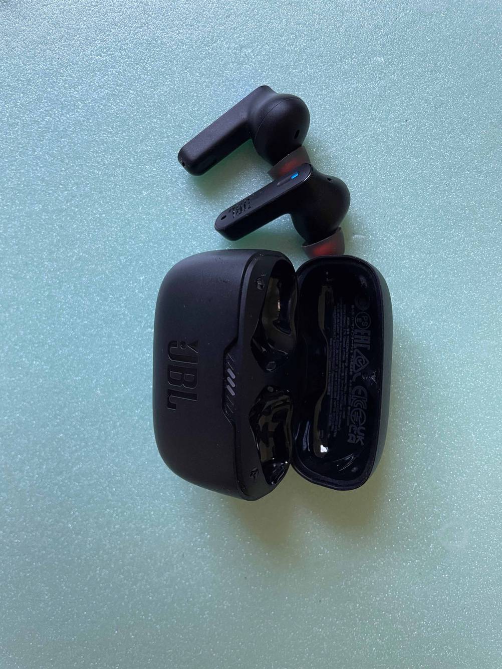 Ein Paar getestete JBL-In-Ear-Kopfhörer liegen neben dem Case.
