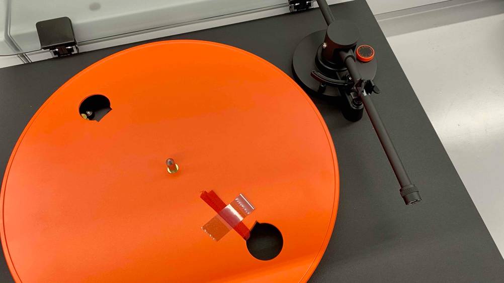 Getestet: Nahaufnahme des orangenen Plattentellers und des Tonarmes eines Bluetooth-Plattenspielers.