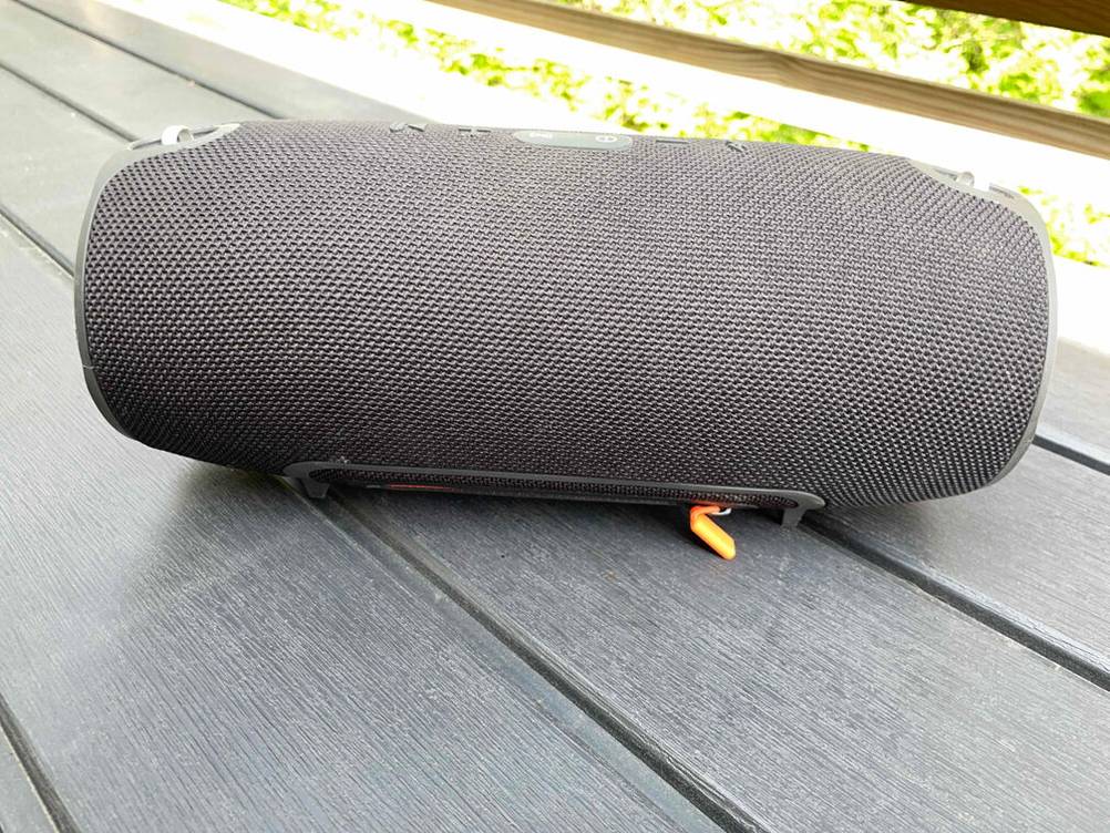 JBL-Bluetooth-Lautsprecher-Test: ein Stereo-Lautsprecher in anthrazit liegt auf einem Holztisch.