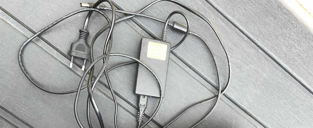 JBL-Bluetooth-Lautsprecher im Test: ein anthrazitfarbenes Ladekabel liegt auf einem grauen Holztisch.