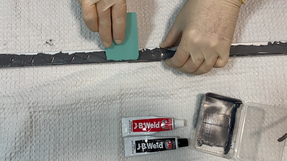 Metallkleber wird mit Schutzhandschuhen aufgetragen.