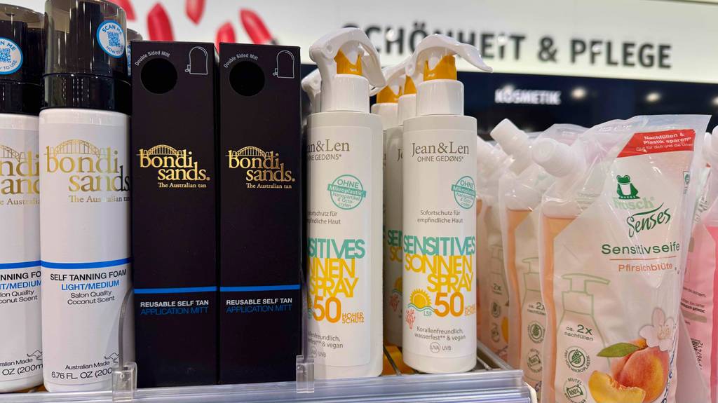 Getestete umweltfreundliche Sonnencremesin weißen Sprühflaschen stehen neben weiteren Sonnencreme-Produkten auf einem Verkaufsregal.