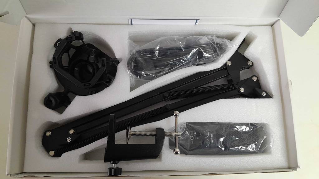 Ansicht eines original verpackten Jeemak USB-Mikrofons im Test inklusive Schwenkarm und Befestigungsvorrichtung.