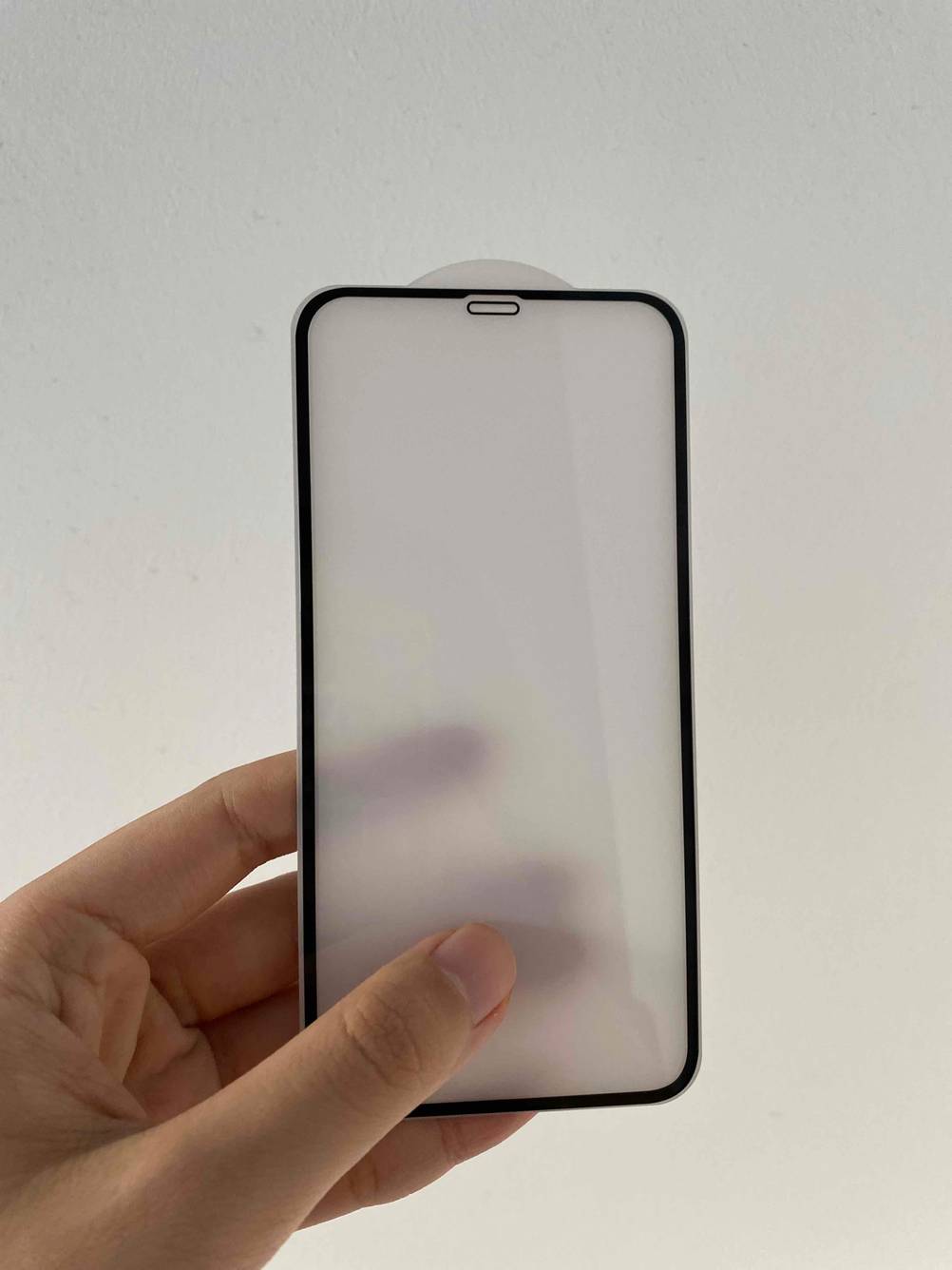 iPhone-Schutzfolie in einer Hand hochgehalten.