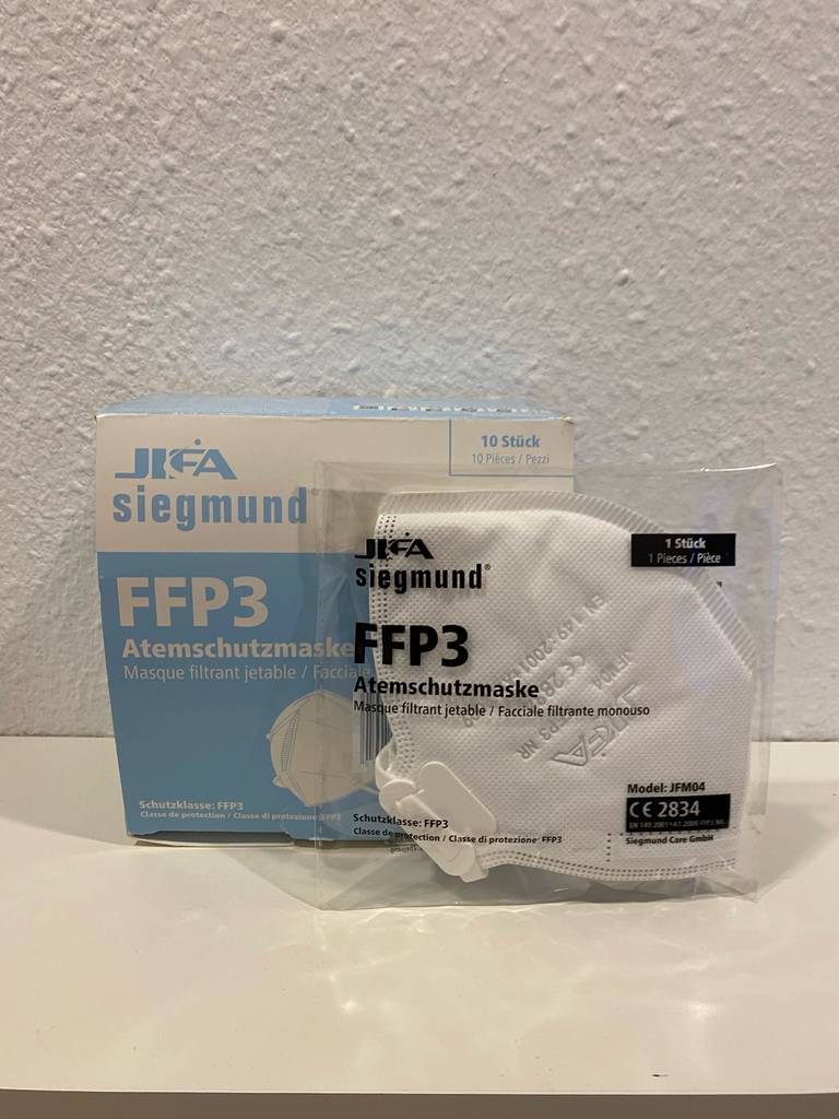 FFP3-Atemschutzmaske-Test: Eine einzelne Atemschutzmaske (FFP3) vor ihrer Originalverpackung vor einer hellen Wand.