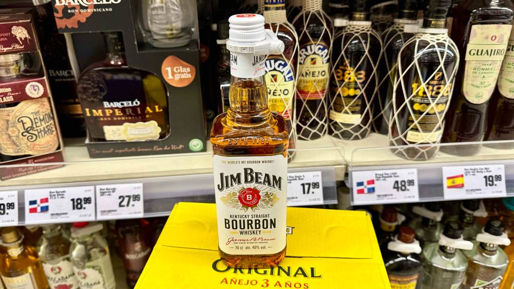 Im Test: Bourbon Whiskey in der Flasche der Marke Jim Beam steht vor einem Regal mit weiteren Spirituosen.