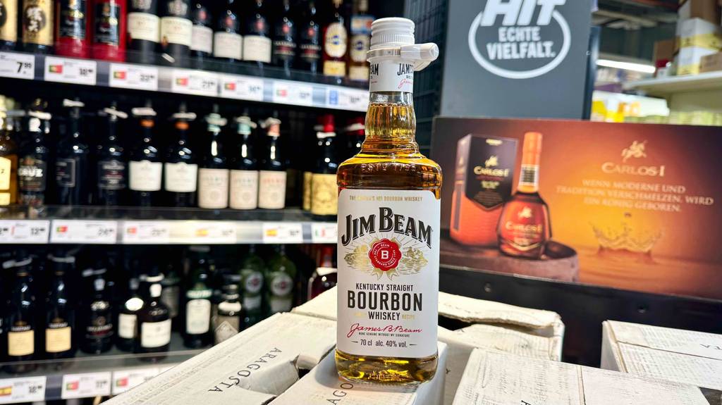 Eine Flasche getesteter Bourbon Whiskey der Marke Jim Beam steht vor einem Verkaufsregal mit alkoholischen Getränken.