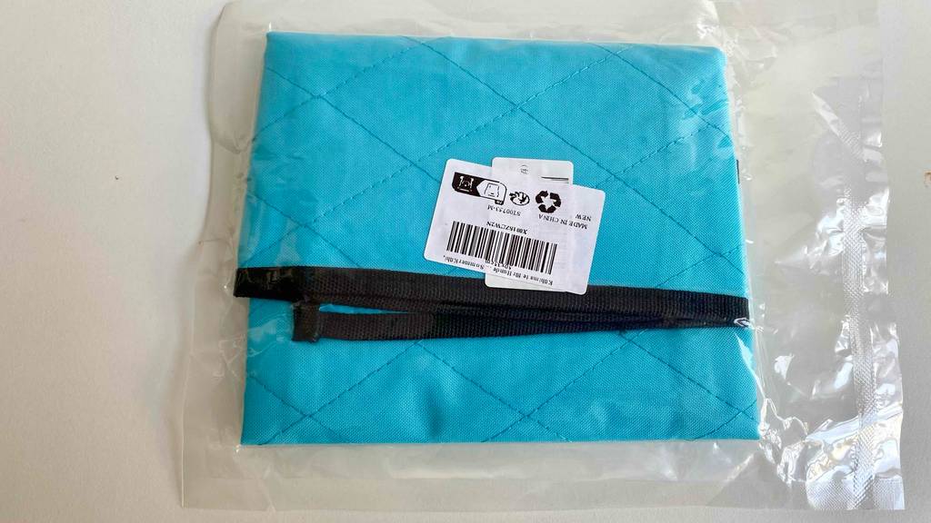 Im Test: Rückseite mit schwarzem Rand einer blauen verpackten Kühlmatte für die Katze.