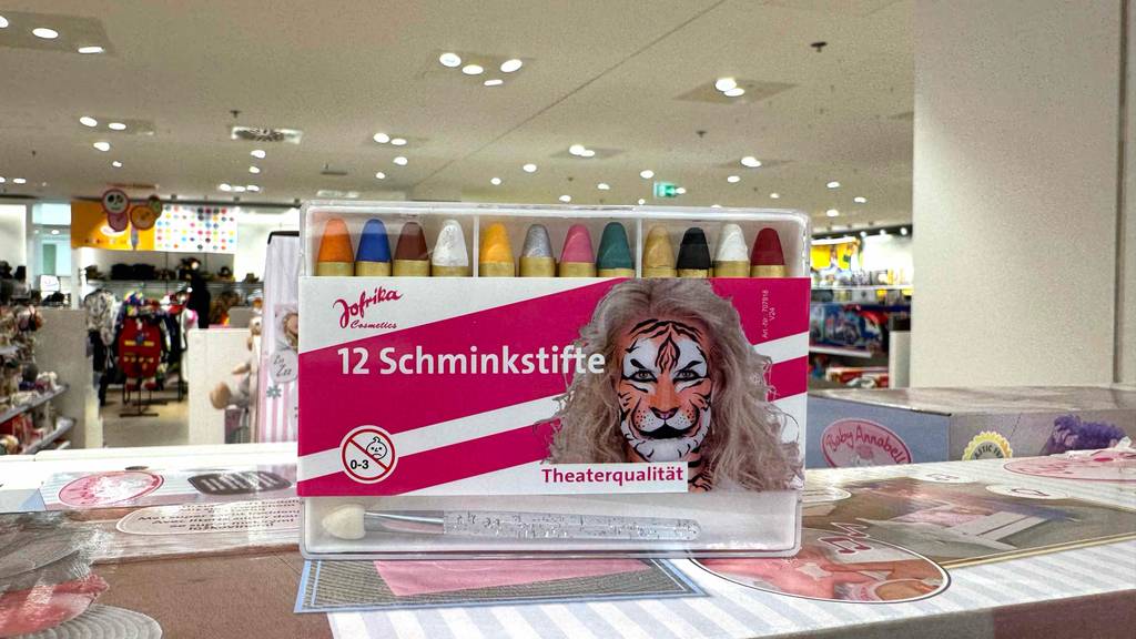 Auf der Frontseite der Aufbewahrungsbox von getesteten Schminkstiften ist ein als Tier geschminktes Gesicht.