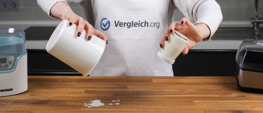 Eine Person gießt zwei Behälter mit Joghurt-Resten aus