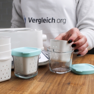 Eine Hand greift nach einem Joghurtbehälter