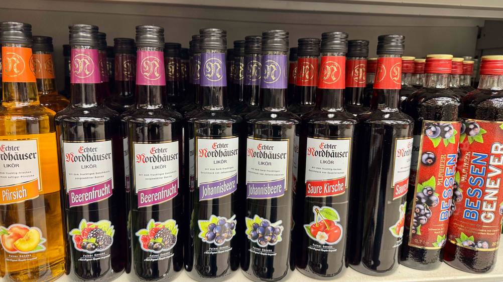 Mehrere Flaschen des Johannisbeerlikörs im Test in einem Verkaufsregal neben anderen Produkten.