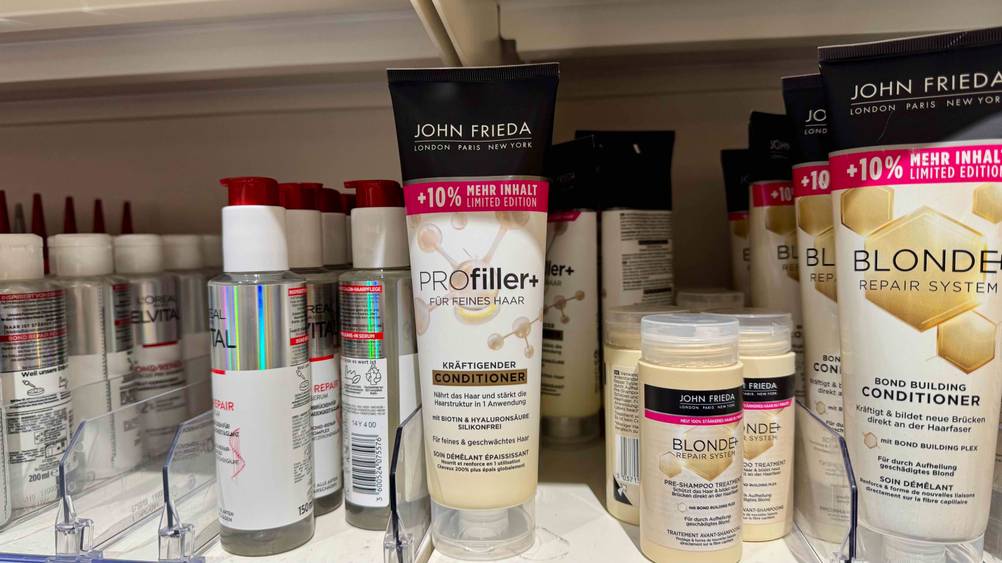 Eine Tube des John-Frieda-Conditioners im Test in einem Verkaufsregal mit mehreren anderen Produkten.