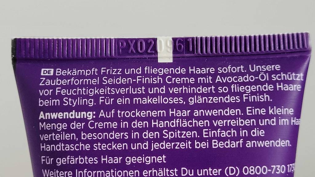 Nahaufnahme der Anwendungsbeschreibung auf einer violettfarbenen Tube einer Haarcreme im Test.