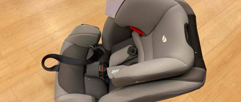 Der getestete Kindersitz steht auf einem Holzboden.