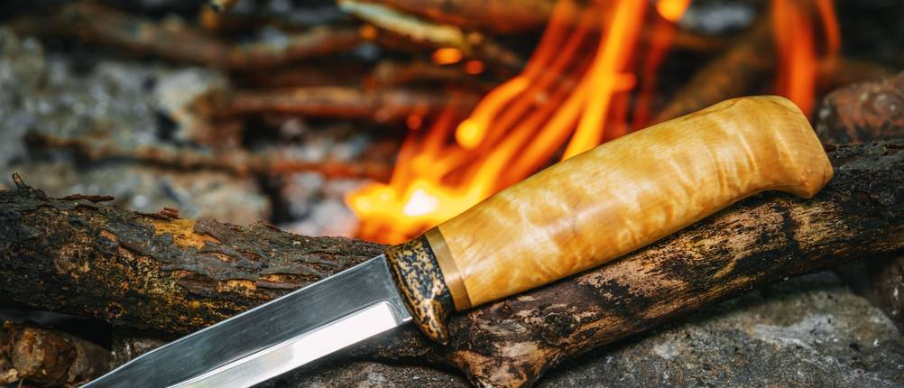 Joker-Messer im Test: Messer mit Holzgriff, Feuer im Hintergrund.