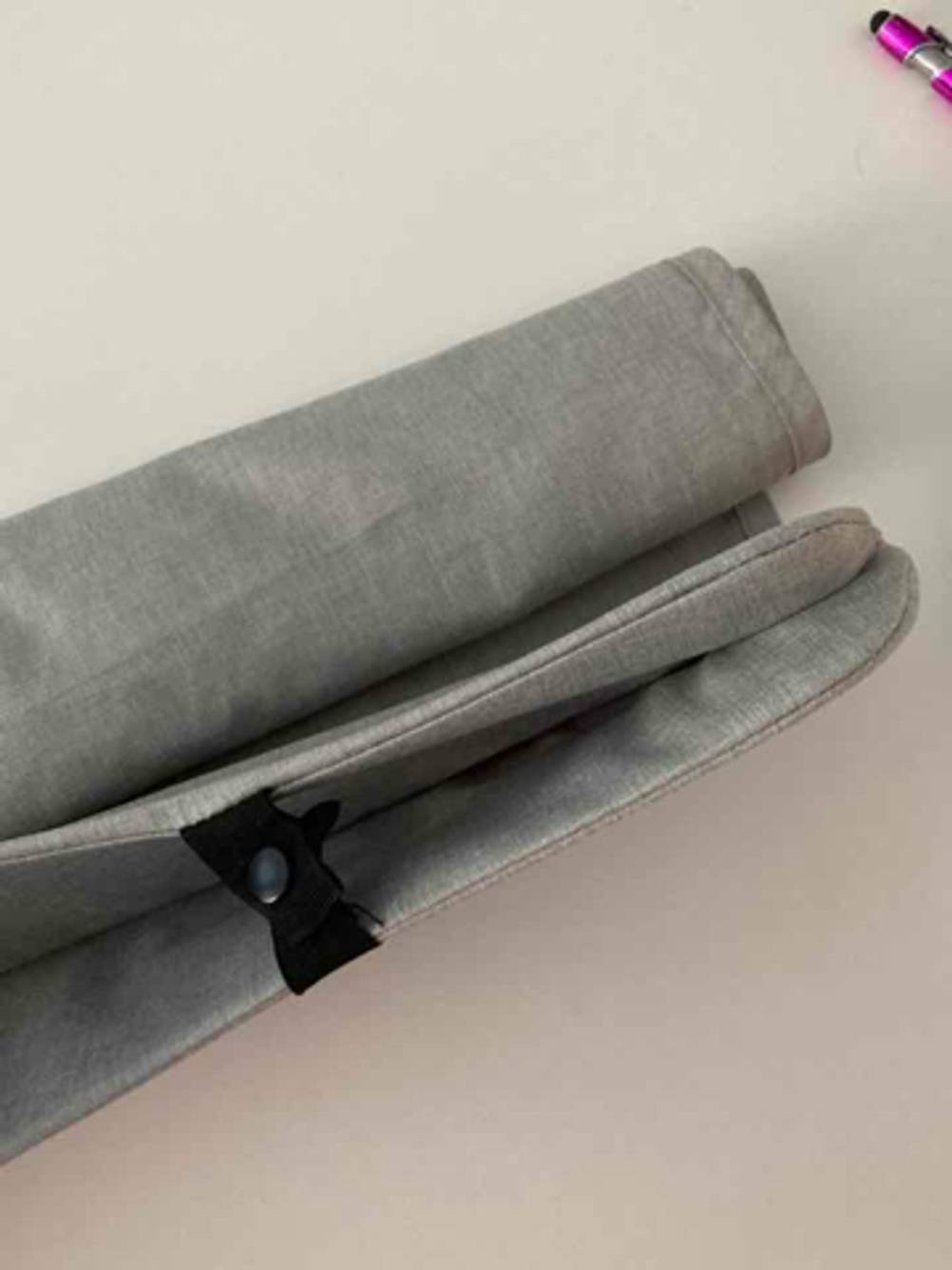 Im Test: der Sonnenschutz für den Kinderwagen liegt zusammengerollt auf einer hellen Oberfläche. 