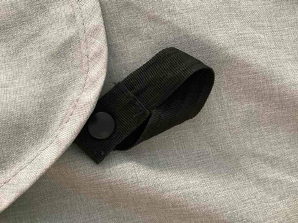 Sonnenschutz-Kinderwagen im Test: Nahaufnahme eines hellgrauen Sonnensegels inklusive eines schwarzen Halteriemens.