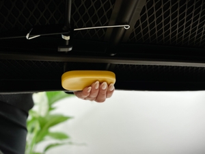 Eine Hand drückt die gelbe Taste an der Unterseite des Joseph-Joseph-Ltd.-Bügelbretts.