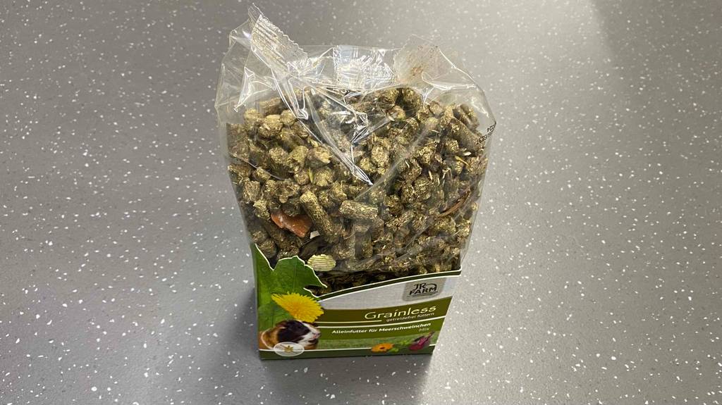 Getestetes Meerschweinchenfutter von Grainless steht in seiner transparenten Verpackung auf grauem Untergrund