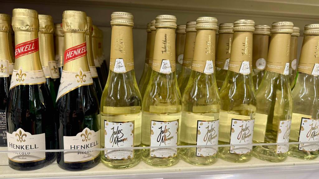 Mehrere Portionsflaschen mit getestetem halbtrockenem Sekt stehen auf einem Verkaufsregal neben anderen Sektfläschchen.
