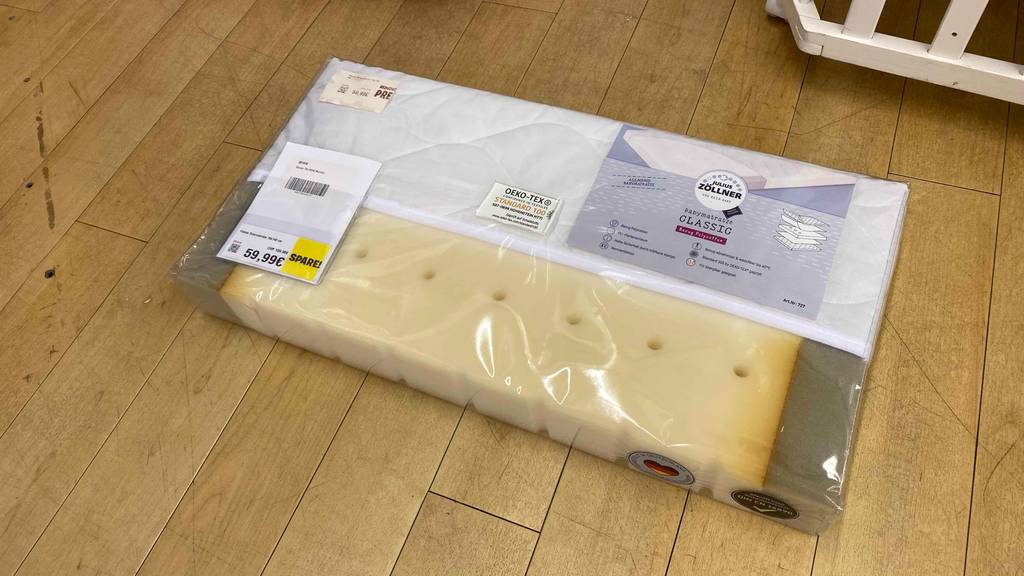 Babymatratzen im Test: ein Schaumstoff-Modell der Marke Julius Zöllner liegt in transparenter Kunststoff-Verpackung auf einem Holzboden.