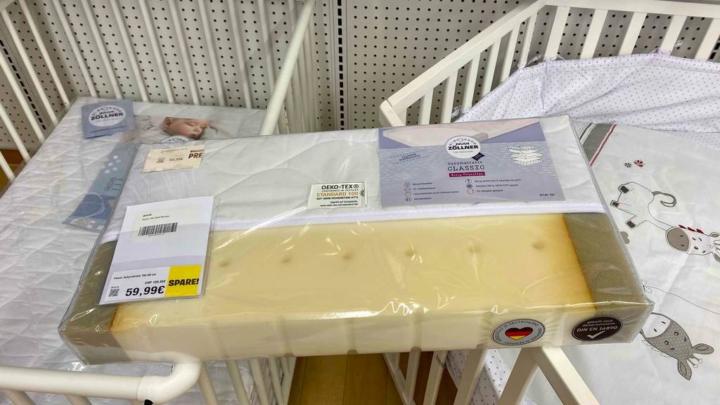 Babymatratzen-Test: ein Schaumstoff-Modell der Marke Julius Zöllner liegt verpackt inklusive Preisschild auf der Umrandung zweier Kinderbetten.