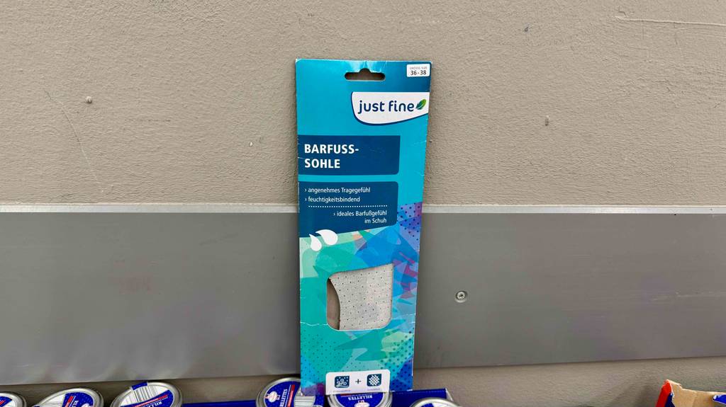 Barfußsohlen-Test: Ein Modell in der blauen Verpackung steht vor einem grauen Hintergrund.
