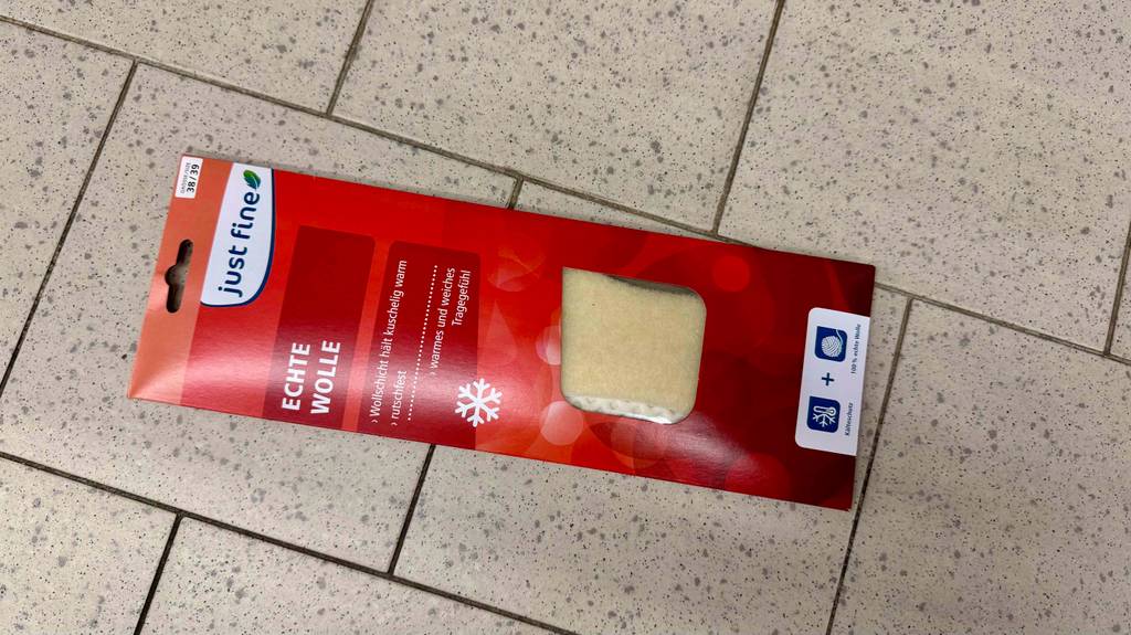 Wärmesohlen-Test: Ein Modell in der roten Verpackung liegt auf einem Fliesenbelag.