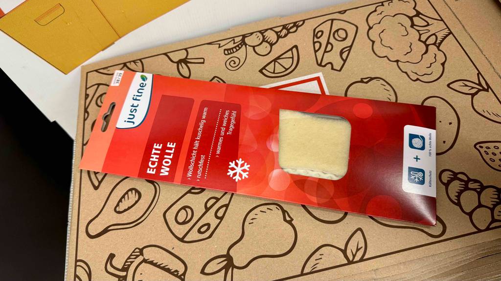 Wärmesohlen im Test: Ein Modell in der roten Verpackung liegt auf einem braunen Karton.