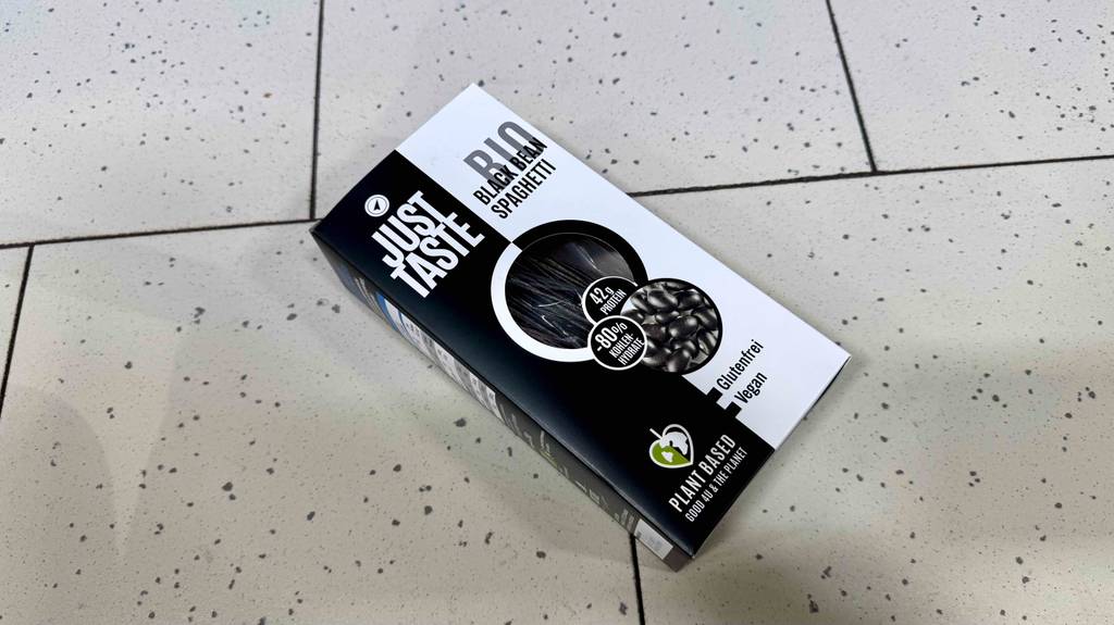 Schwarze Spaghetti getestet: Eine Packung liegt schräg auf einem Fliesenboden.
