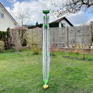 Die Juwel Novaplus 600 Lift steht zusammengeklappt im Garten. Die Leinenarme sind kompakt eingefaltet.