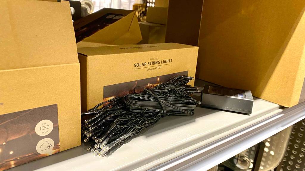 Solar-Lichterkette für Außen im Test: eine schwarze Lichterkette liegt, ausgestellt auf einem Verkaufsregal, vor ihrem hellbraunen Verpackungskarton.