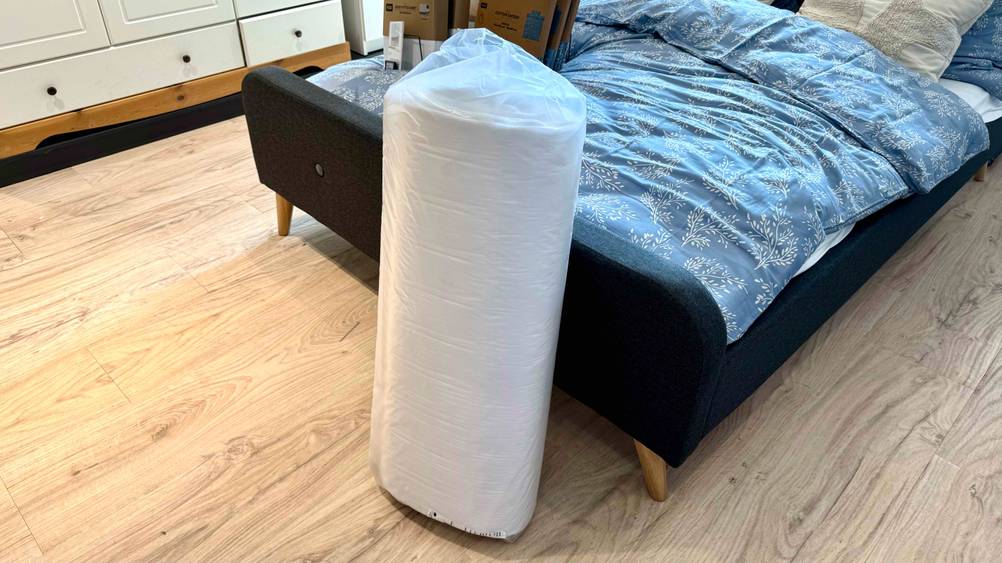 Getesteter Topper 80 x 200 lehnt an einem Bett.