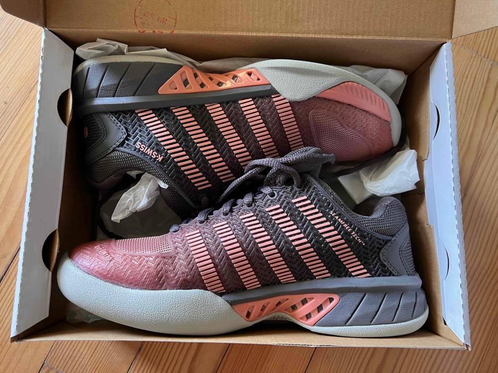 Tennisschuhe in Rot-Schwarz im Karton liegend.