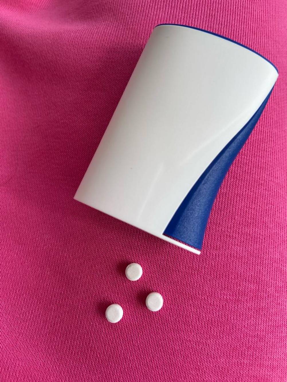 Der weiß-blaue Natreen-Süßstoffspender im Test liegt neben drei Süßstofftabletten.