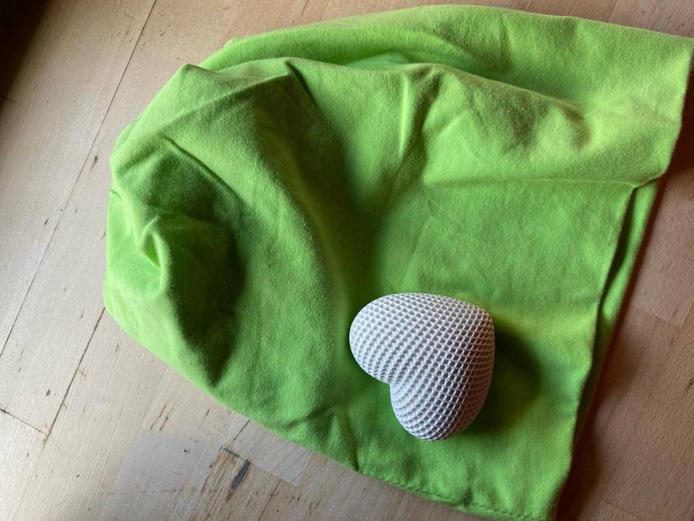 Beanie-Test: Auf der grünen Mütze liegt ein weißws dekoratives Herz.
