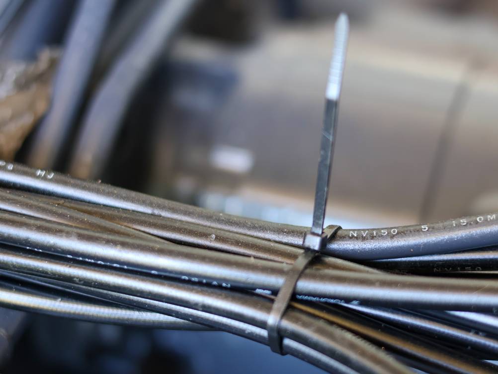 Kabelbinderzange im Test: Ein Kabelbündel (schwarz) wird von einem schwarzen Kabelbinder gehalten, der nicht abgeschnitten ist.