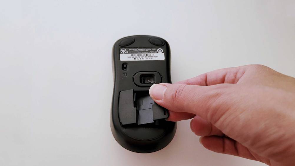 Kabellose Maus getestet: Eine Hand öffnet das Batteriefach auf der Rückseite.