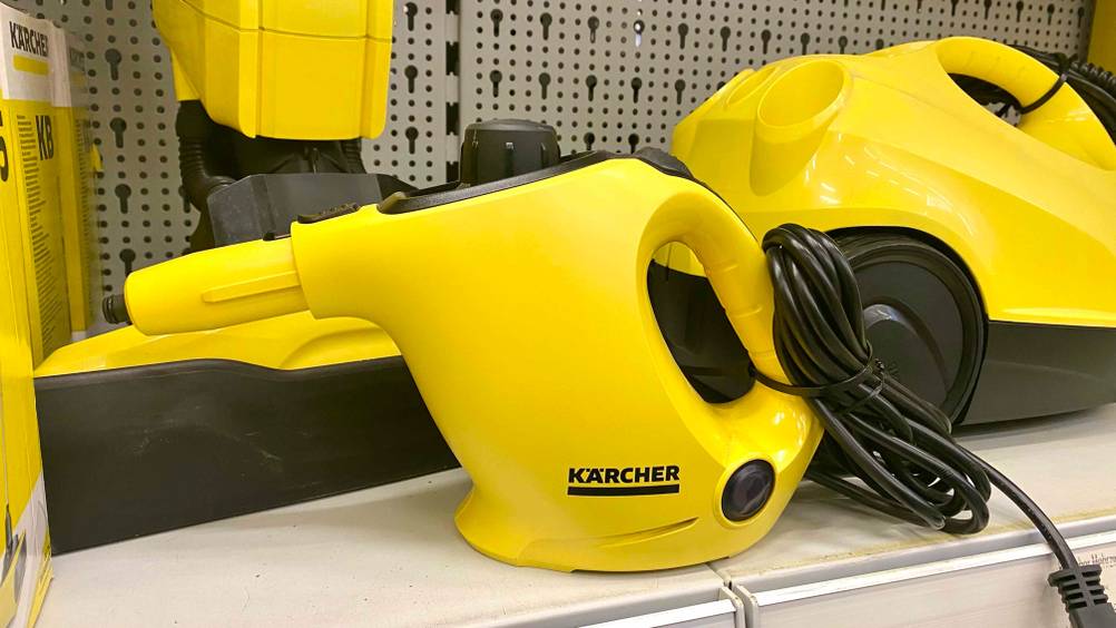 Ein Dampfreiniger von der Seite neben anderen Produkten im Regal stehend.